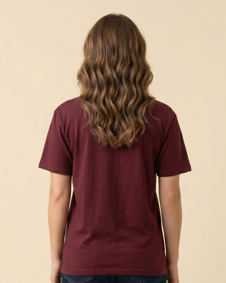 Person wearing a maroon t-shirt and dark jeans on a beige background
