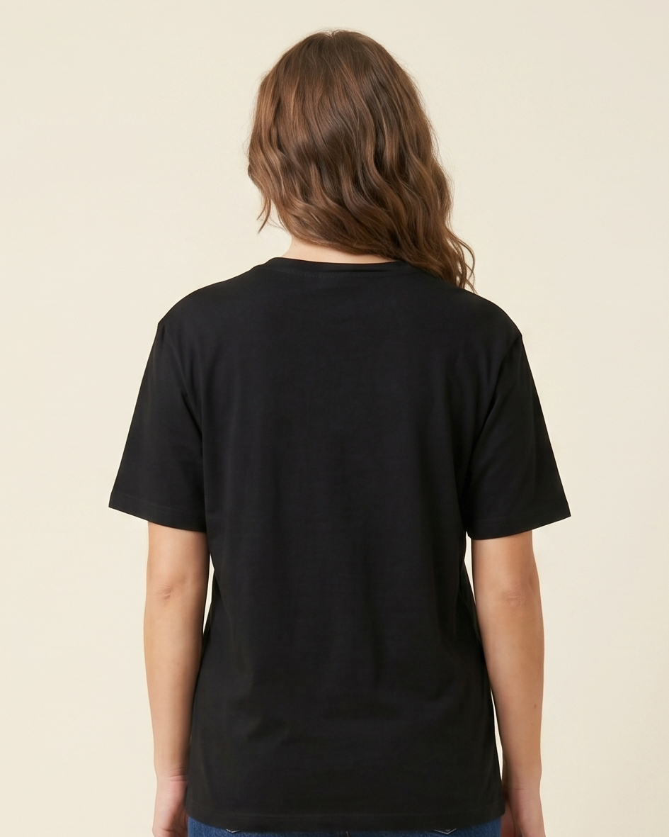 Person wearing a black t-shirt and blue jeans standing against a beige background