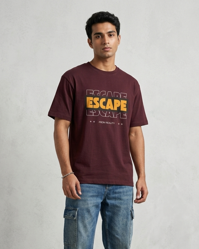 Man wearing a maroon t-shirt with 'ESCAPE' text and blue jeans on a plain background