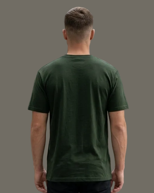 Man wearing a green t-shirt and black pants standing in a grey.