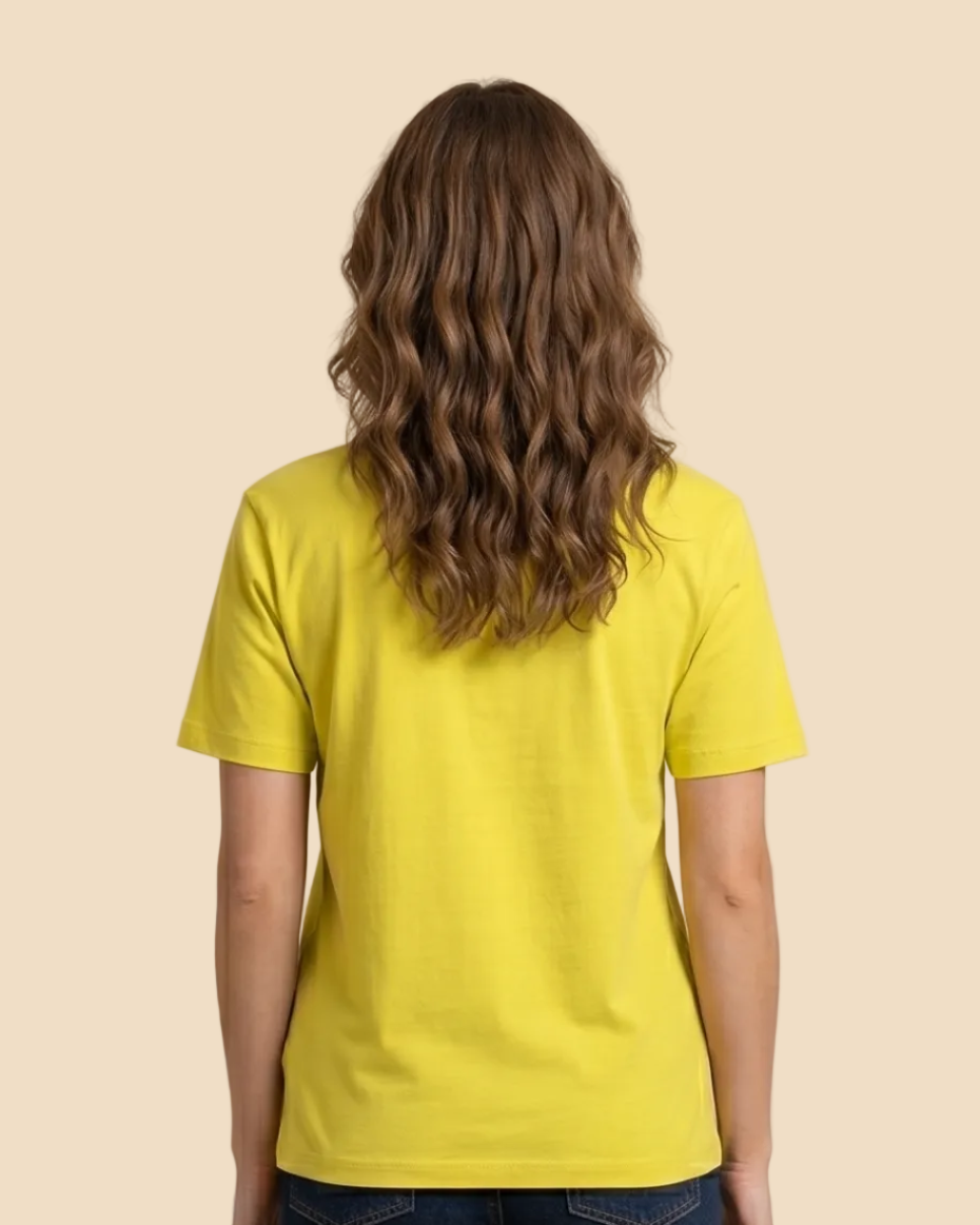 Person wearing a yellow t-shirt and blue jeans against a beige background