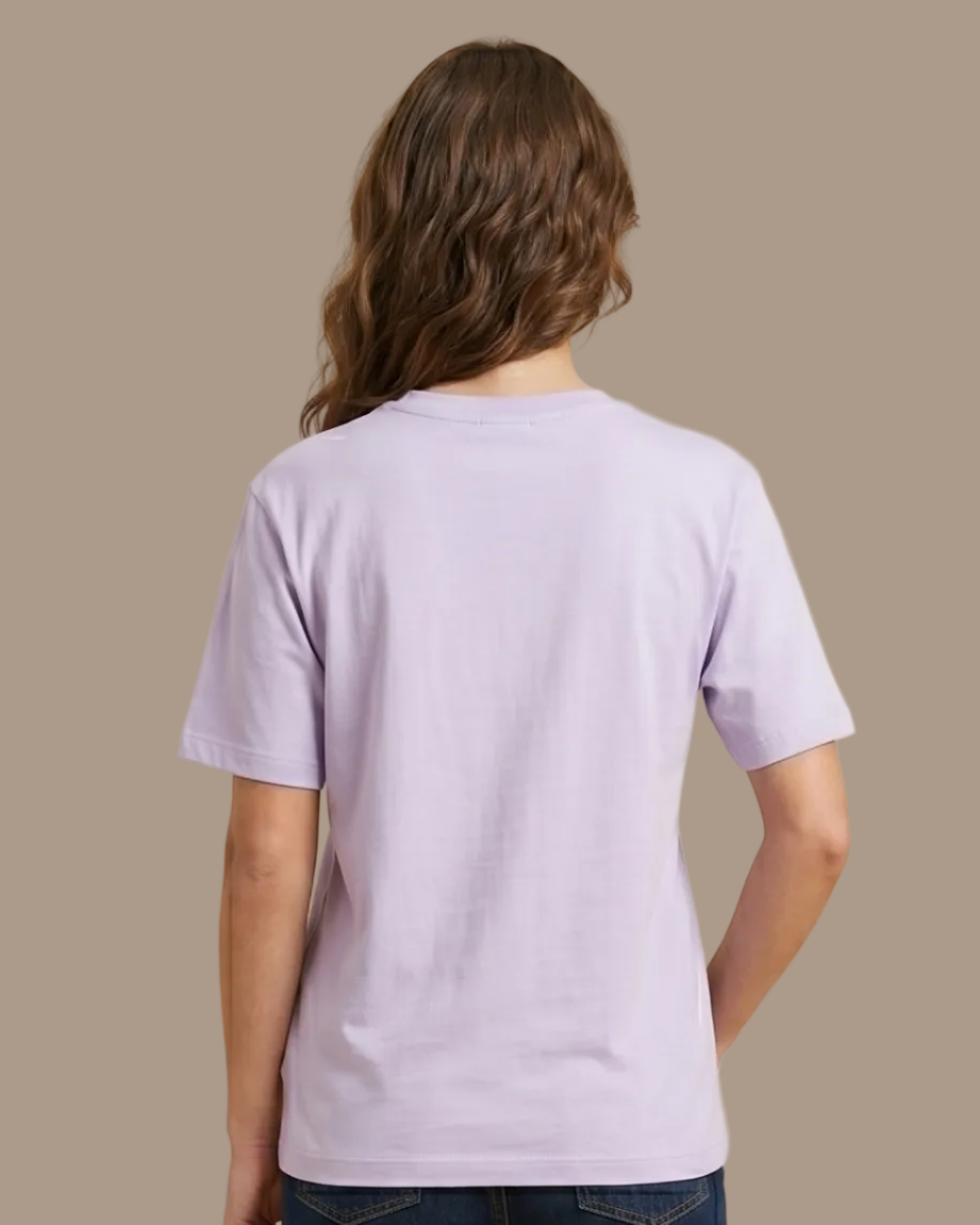 Person wearing a light purple t-shirt and dark blue jeans on a beige background