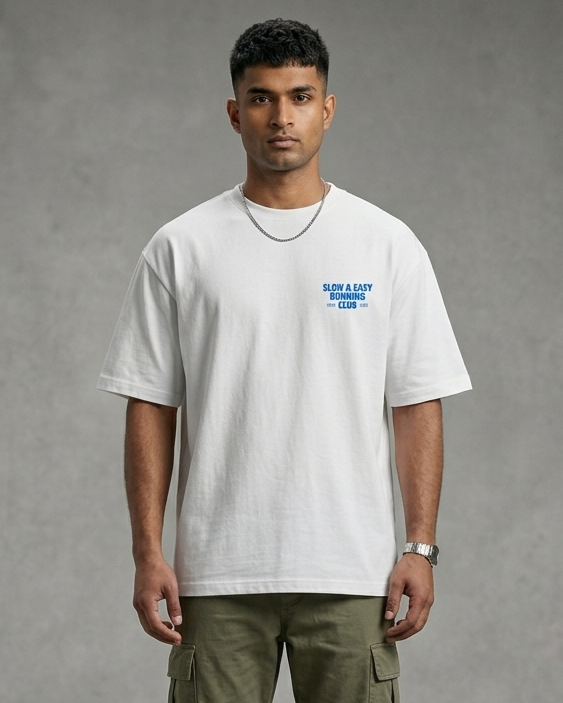 Man wearing a white t-shirt with a logo and green pants on a gray background