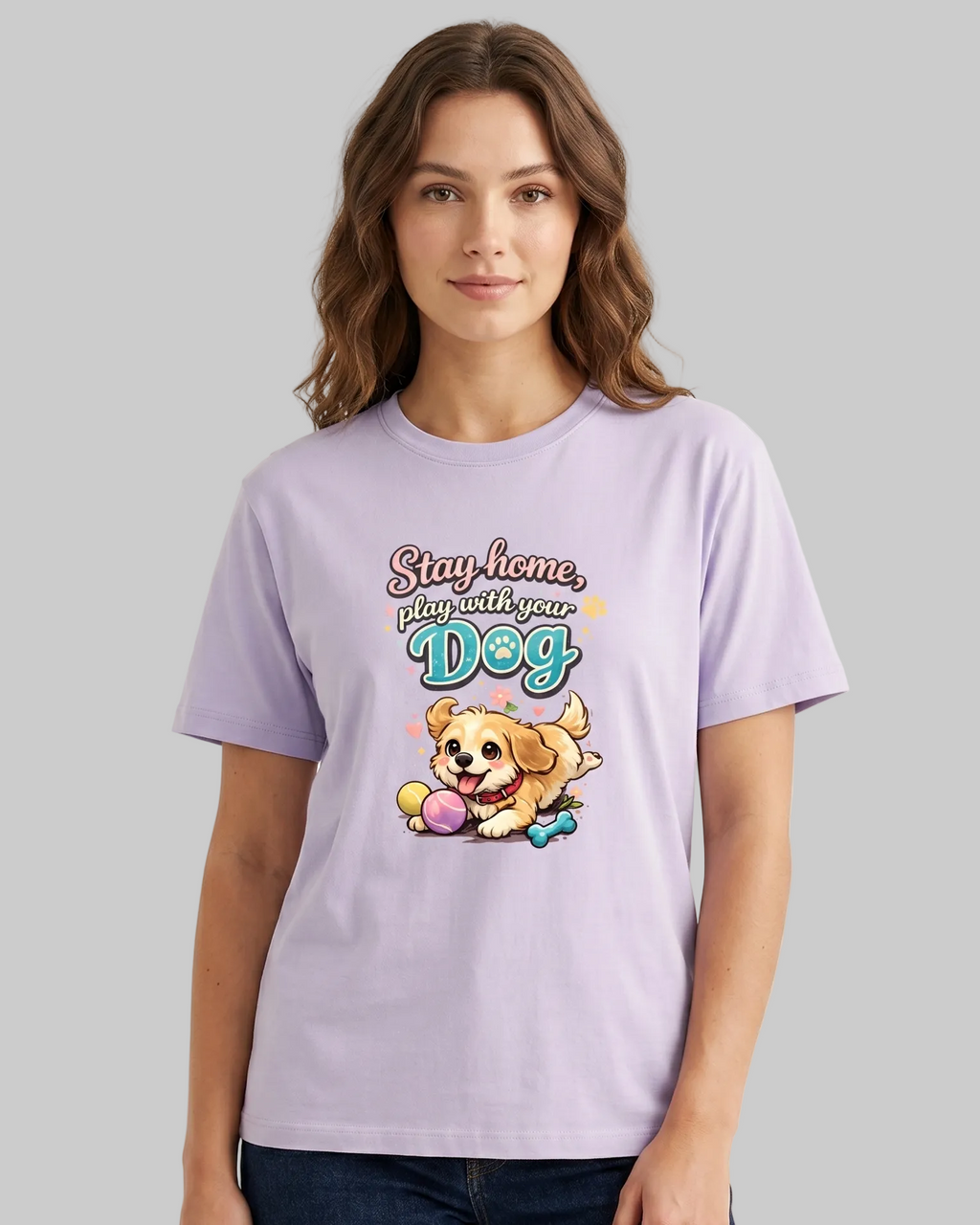 Woman wearing a lavender t-shirt with a graphic and text 'Stay home, play with your dog' on a plain background