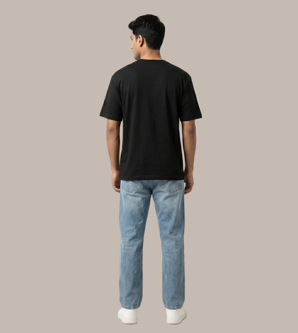Person wearing a black t-shirt and light blue jeans on a white background