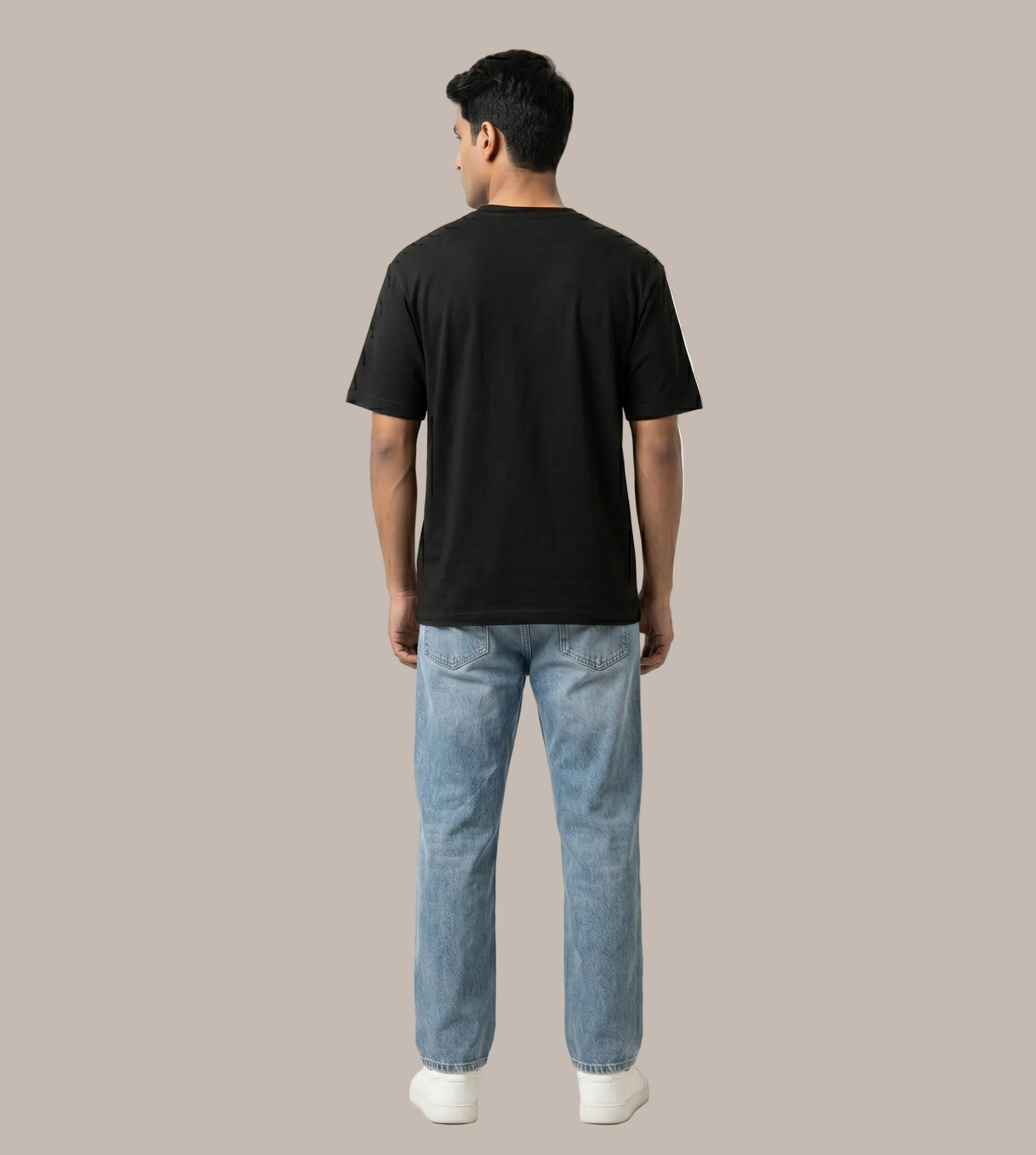 Person wearing a black t-shirt and light blue jeans on a white background