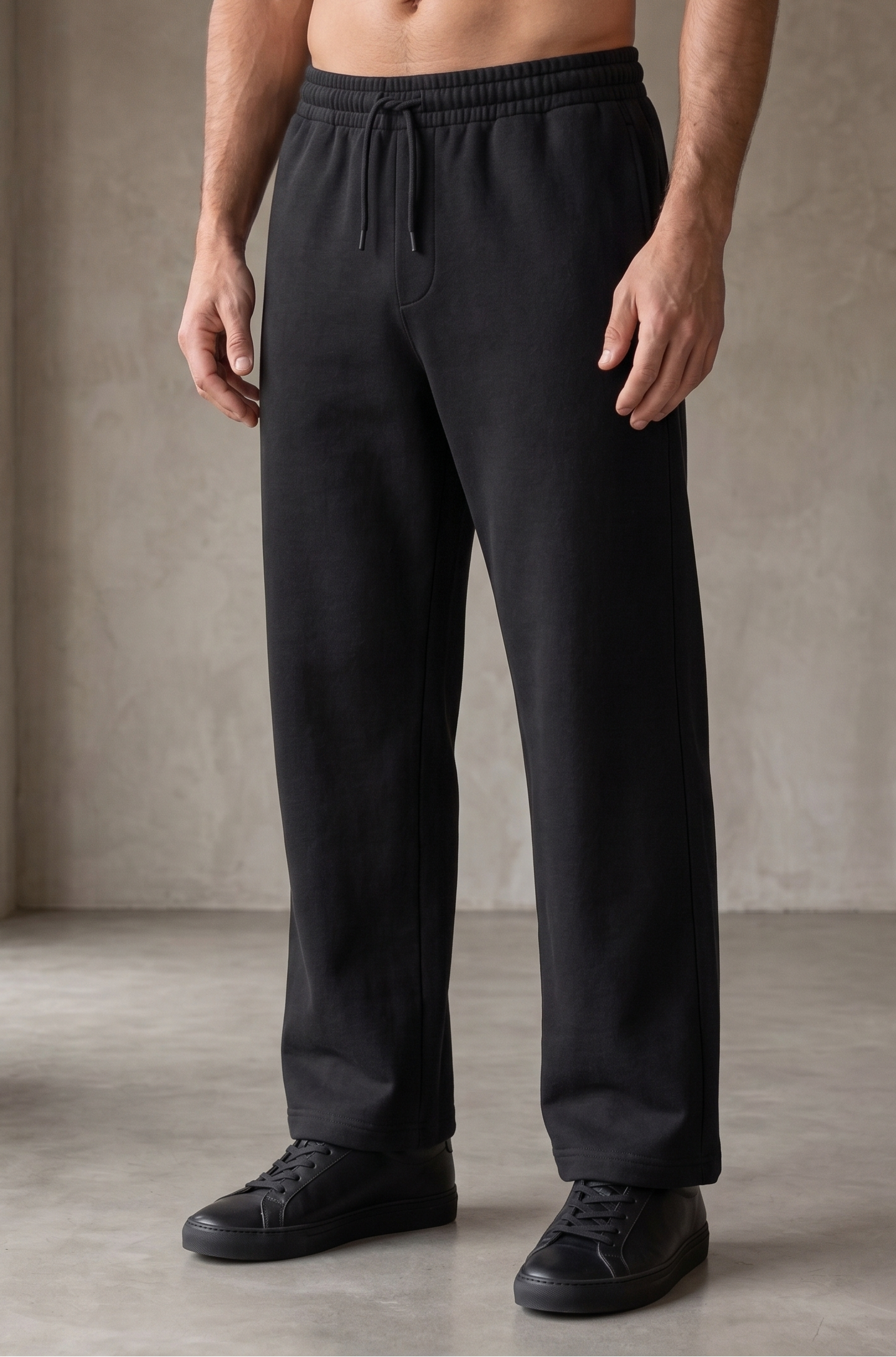 Man wearing black pants standing against a neutral background