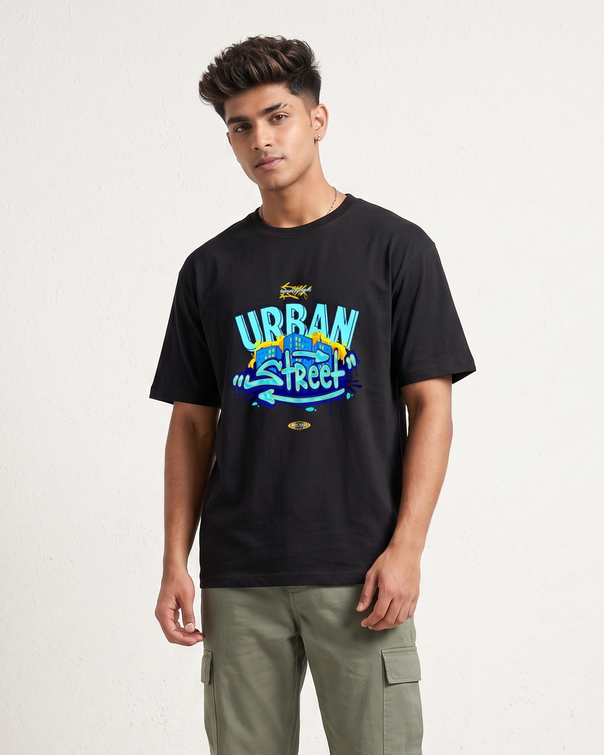 Person wearing a black t-shirt with colorful text and green pants on a white background