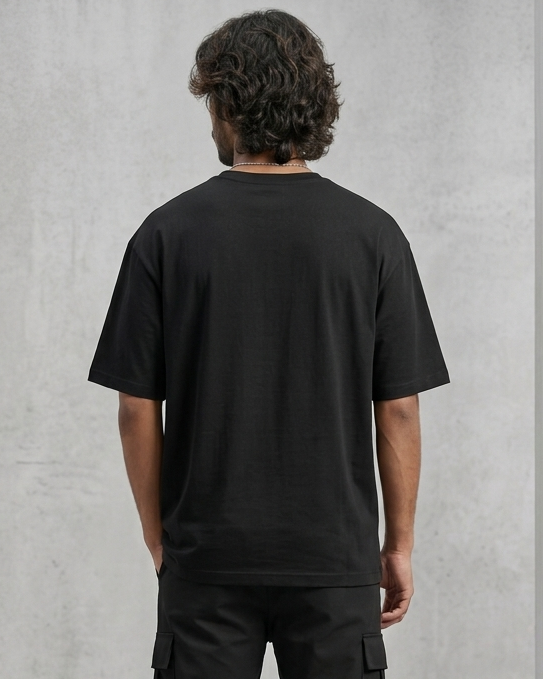 Person wearing a black t-shirt and pants against a gray concrete wall.