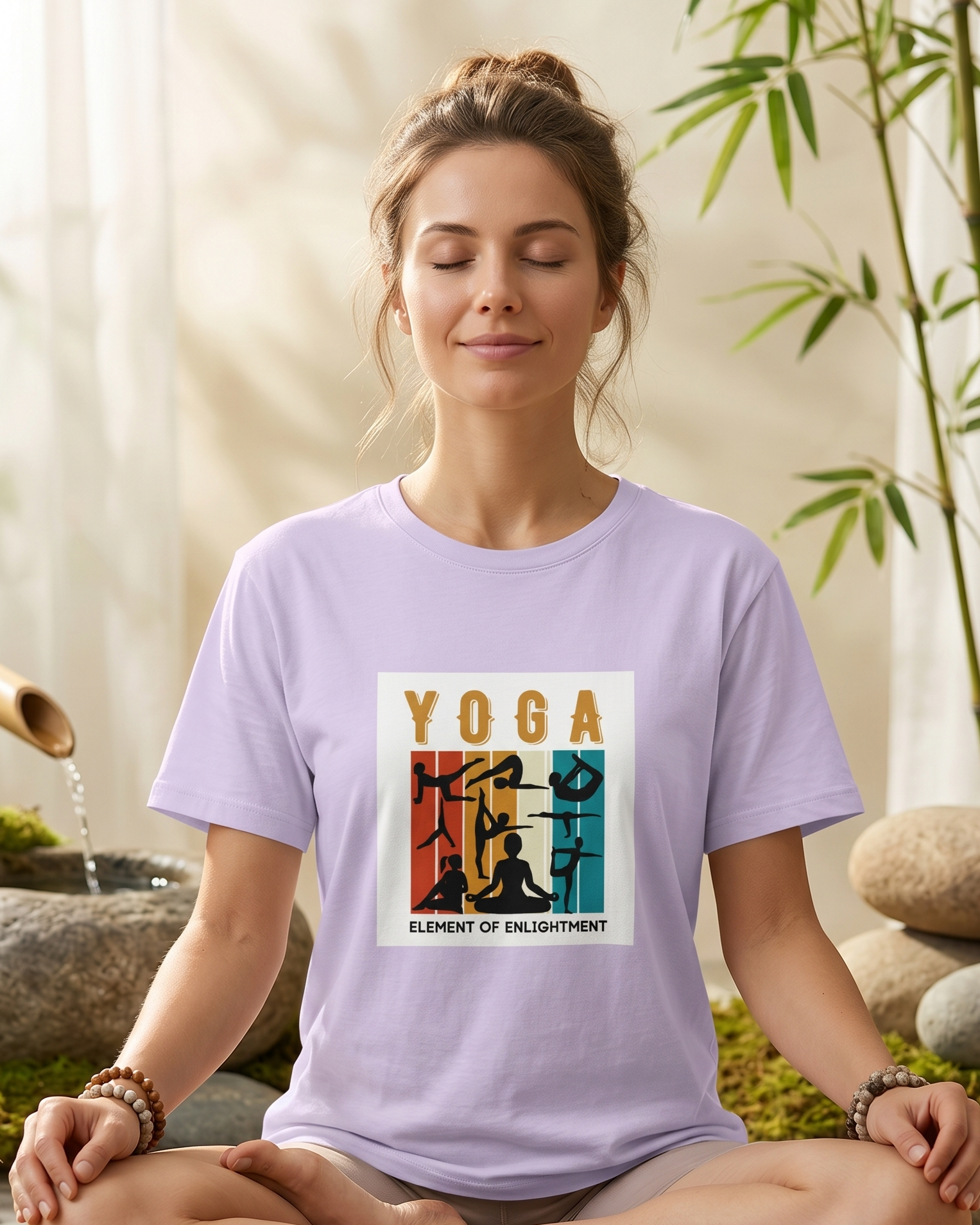 Woman sitting in a yoga pose wearing a purple t-shirt with a yoga design, in a serene setting with bamboo and stones.